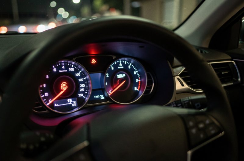 Tableau de bord de voiture moderne, éclairage nocturne réaliste, témoin de moteur allumé et indication lumineuse de contrôle, ambiance de conduite quotidienne.