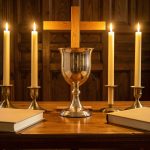 Autel d’église lumineux présentant un calice, des cierges allumés, une croix en bois et des livres liturgiques fermés dans une ambiance solennelle.